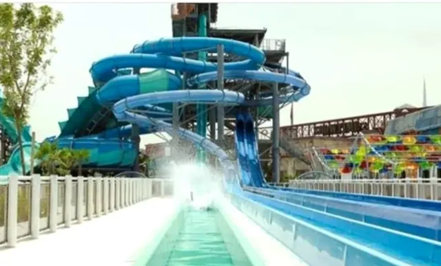מגלשות מים כחולות מפותלות ומסלולי החלקה מקבילים לצד מבנה מתכת