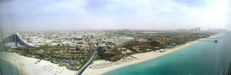 מבט מלמעלה על רצועת חוף ארוכה עם שמשיות, ולצדה גינון ודרך