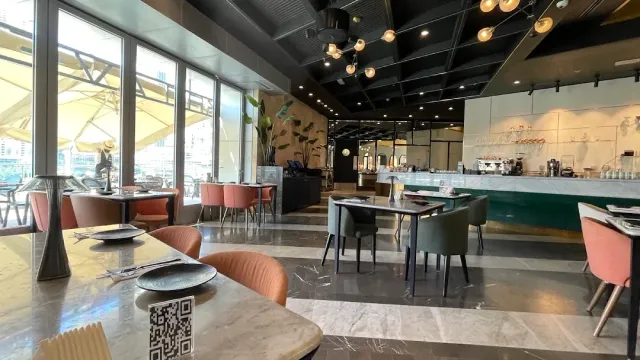 חלל עם כיסאות ורודים וירוקים, שולחנות שיש, דלפק ותאורת נורות תלויה