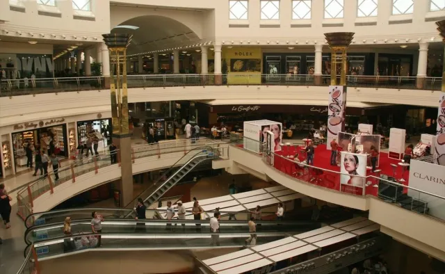 אטריום קניון עם מעקות מעוגלים בשתי קומות ותצוגה מרכזית אדומה