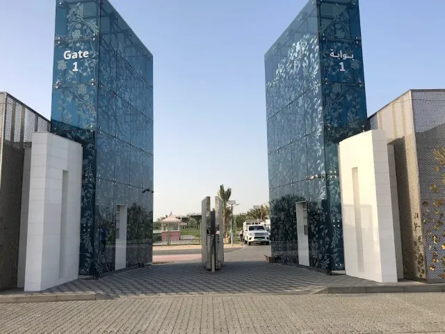 שערי זכוכית כחולים בדוגמת צמחייה בכניסה, ומאחוריהם שביל ועצים