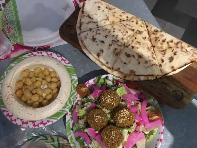 מגש ובו חומוס, כדורי פלאפל, ירקות חתוכים ולחם שטוח