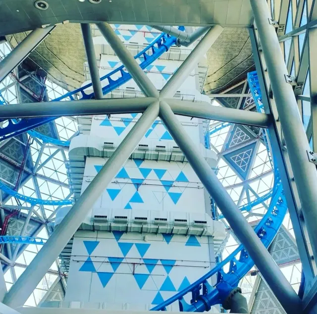מסילת רכבת הרים כחולה מתפתלת סביב מגדל לבן בדוגמת משולשים תכולים