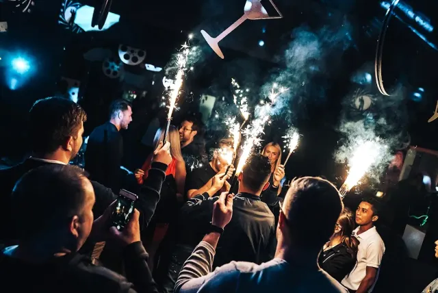 קהל במועדון לילה מרים זיקוקים נוצצים ומצלם בטלפונים