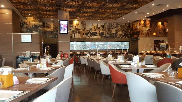 אולם גדול עם קיר תצלומים, מזנון מרכזי וכיסאות בכתום ובלבן