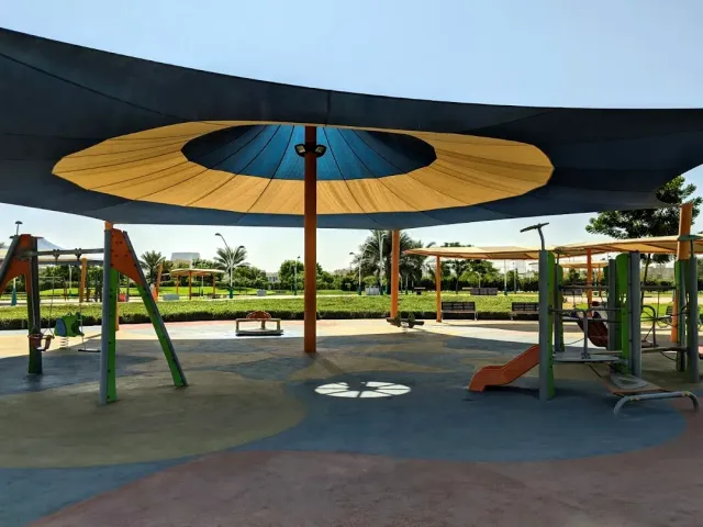 מתקני משחקים צבעוניים מתחת ליריעות הצללה עגולות בכחול וצהוב