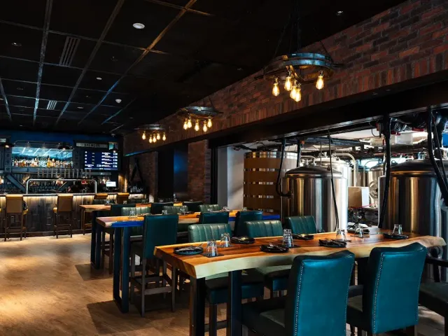מכלי בישול ממתכת מאחורי שולחנות עץ וכיסאות עור בטורקיז