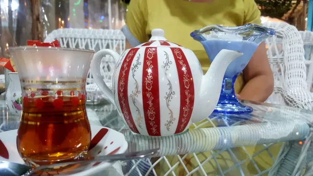 קנקן מפוספס וכוס תה על שולחן נצרים לבן