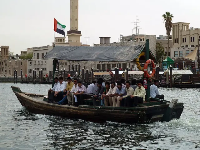סירת עץ מלאה נוסעים חוצה תעלת מים מול בתי העיר העתיקה