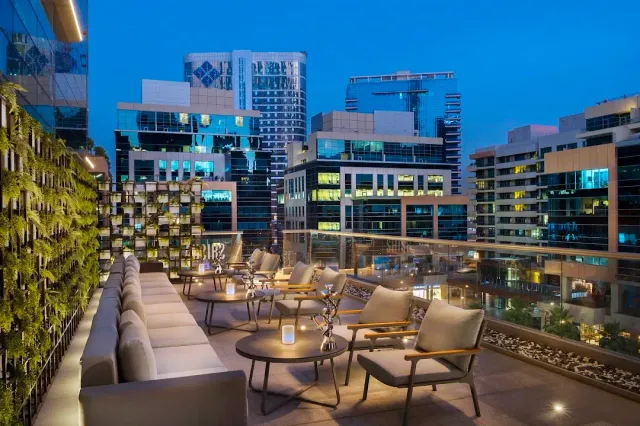 מרפסת ערב עם ספות וכורסאות נמוכות, נרות על שולחנות ומגדלים מוארים