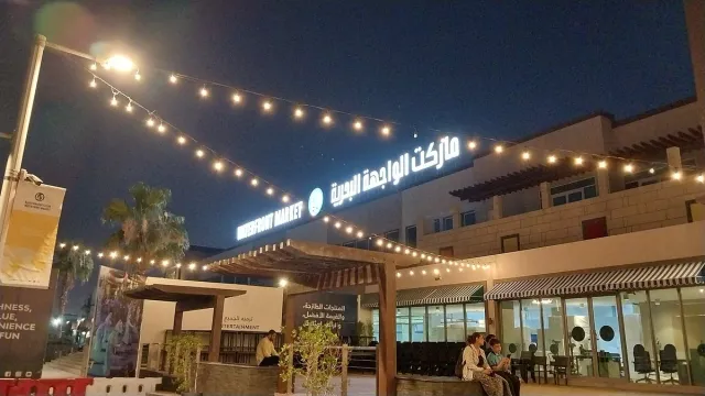 חזית שוק מוארת בשלט זוהר ובשרשרות נורות בשעת ערב